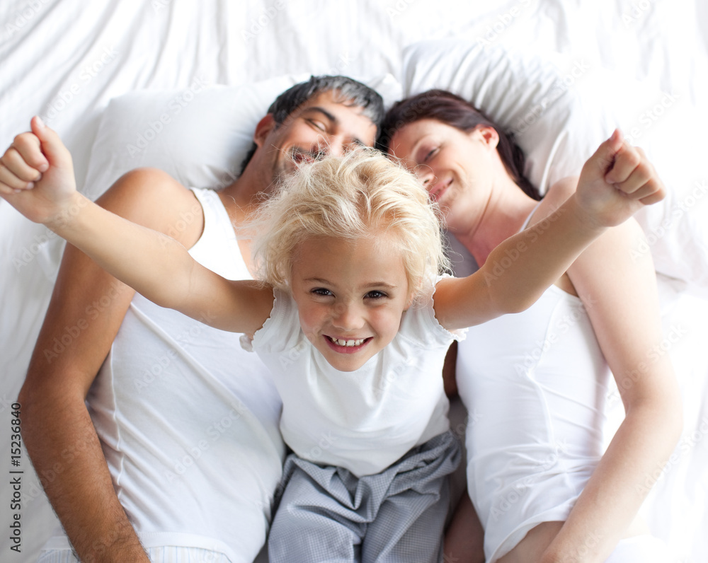 Happy little girl on bed with her parents Happy little girl on bed with her parents