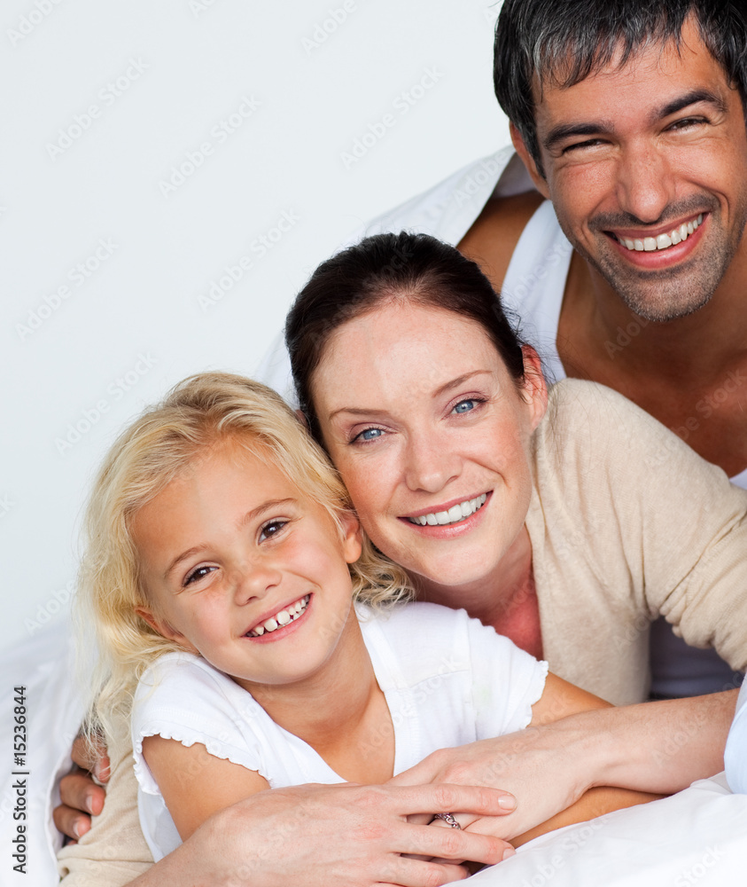 Parents and daughter on bed smiling at the camera Parents and daughter on bed smiling at the camera