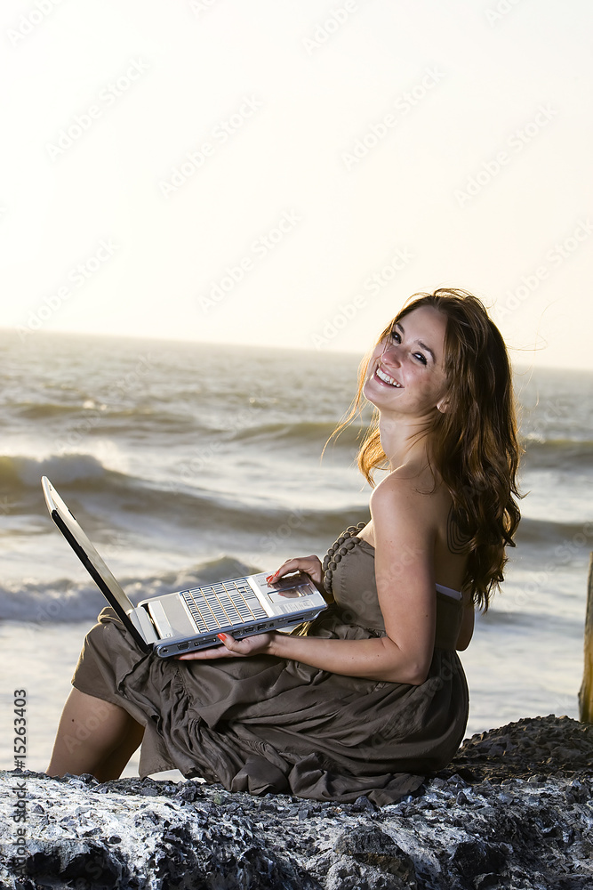 Pretty Girl working on laptop at the beach