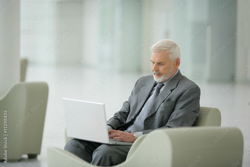 homme actif assis dans un fauteuil devant un ordinateur homme actif assis dans un fauteuil devant un ordinateur