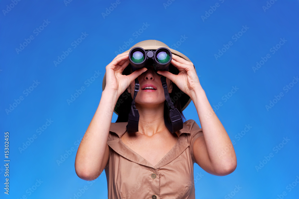 Woman in safari hat looking through binoculars Woman in safari hat looking through binoculars
