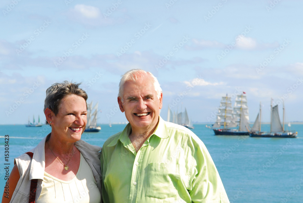senior smiling couple with scenic ocean and sailboats background