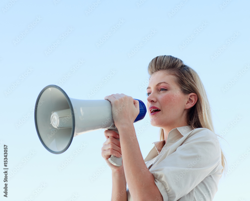 Blonde businesswoman shouting through megaphone Blonde businesswoman shouting through megaphone