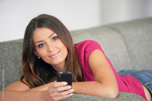Jeune femme assise sur un canapé avec téléphone portable
