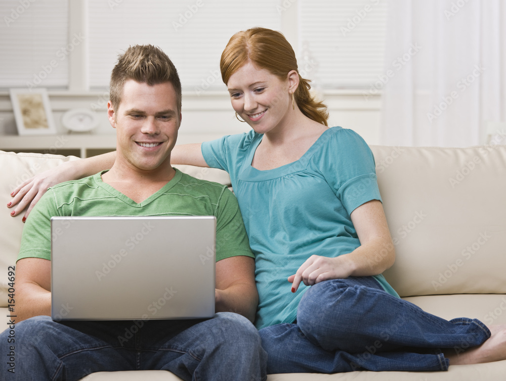 Couple Viewing Laptop Together on the Couch Couple Viewing Laptop Together on the Couch