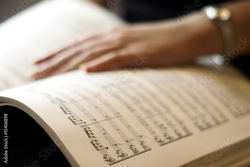 Female hand on musical score book page photo