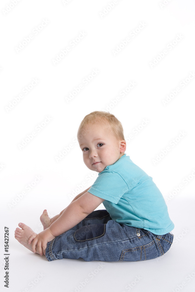 Toddler boy sitting on the floor looking into the camera Toddler boy sitting on the floor looking into the camera