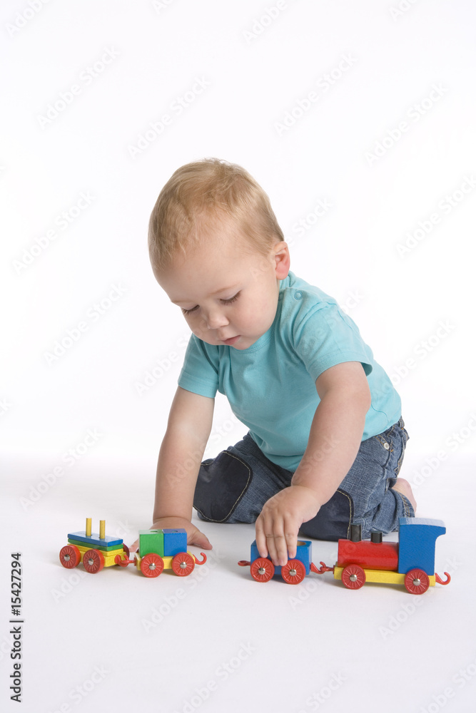 Toddler boy playing with a wooden toy train Toddler boy playing with a wooden toy train