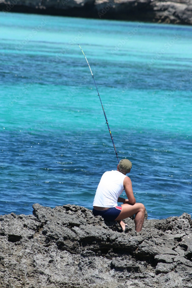 Foto Stock pescatore in riva al mare sugli scogli | Adobe Stock