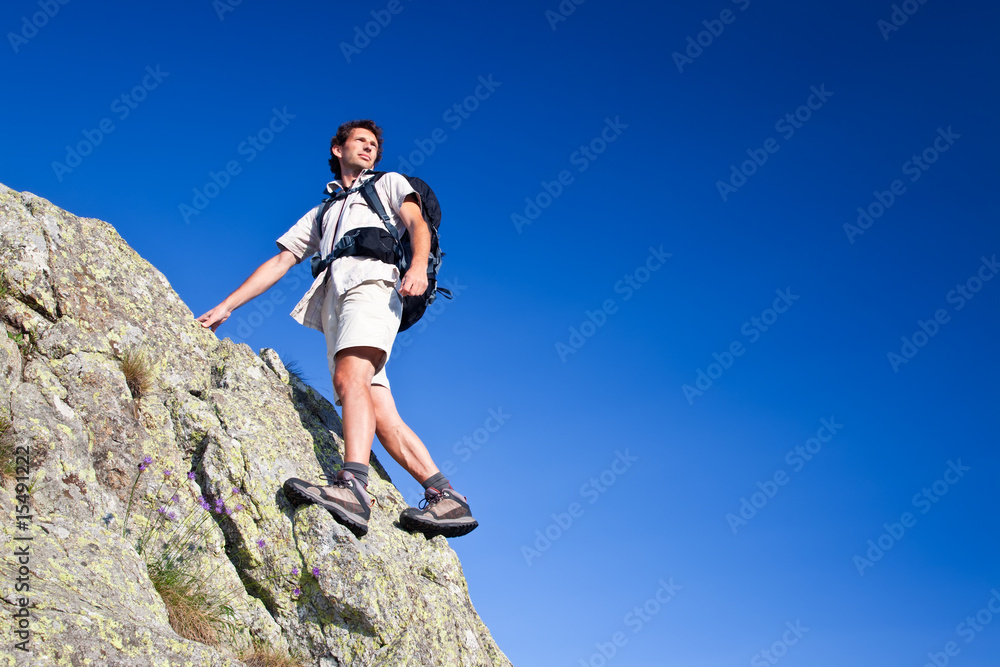 Young man standing on a rock over a deep blue sky