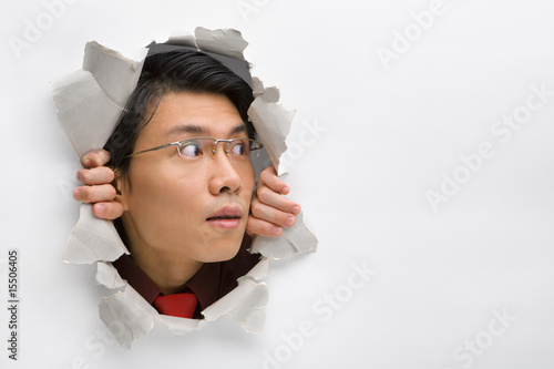 Man looking away to his left side from hole in wall