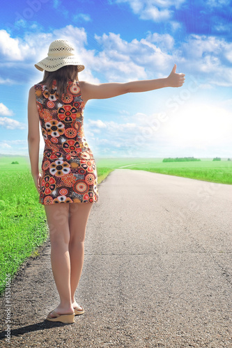 Back of woman hitchhiking the road
