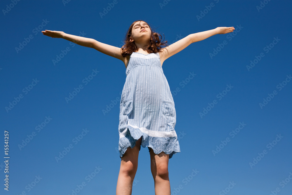 Hope - girl holding arms up against blue sky Hope - girl holding arms up against blue sky