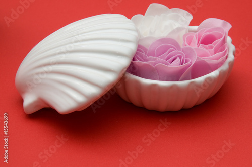Clay shell holder of soap roses on red background
