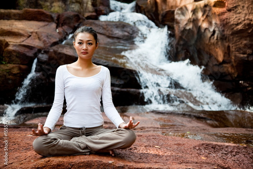 Woman doing zen exercise near a waterfall