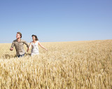 couple running in wheat field