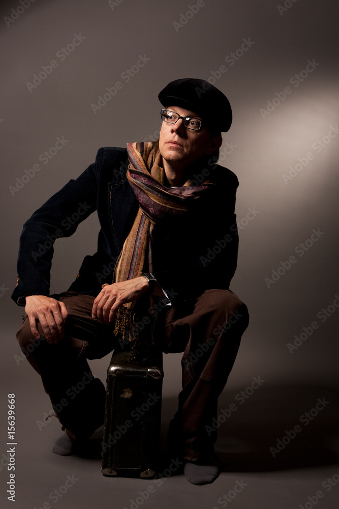 man in cap sitting on suitcase isolated man in cap sitting on suitcase isolated
