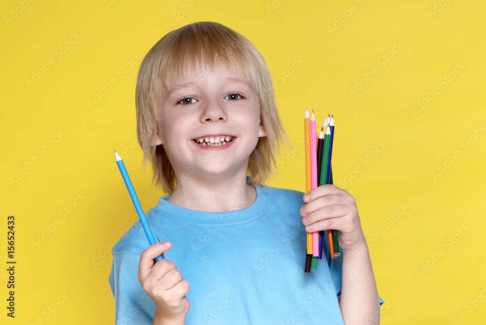 The small schoolboy with pencils on a yellow background The small schoolboy with pencils on a yellow background