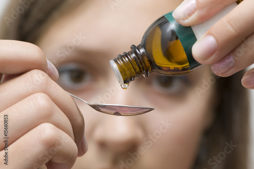 Dripping herbal essence of a vial over a spoon