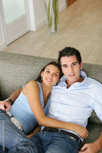 Portrait d'un jeune couple souriants assis sur un canapé
