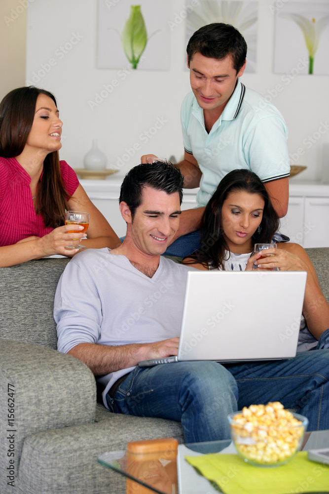 Groupe d'amis devant un ordinateur portable avec un verre de vin Groupe d'amis devant un ordinateur portable avec un verre de vin