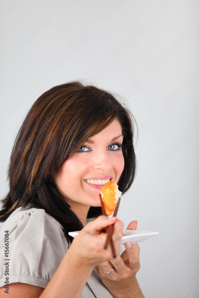 femme souriante mangeant un sushi sur fond blanc femme souriante mangeant un sushi sur fond blanc