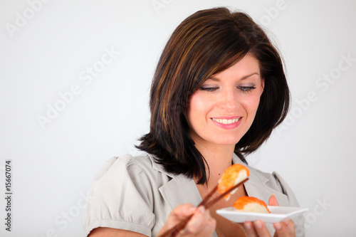 femme souriante mangeant des sushis sur fond blan