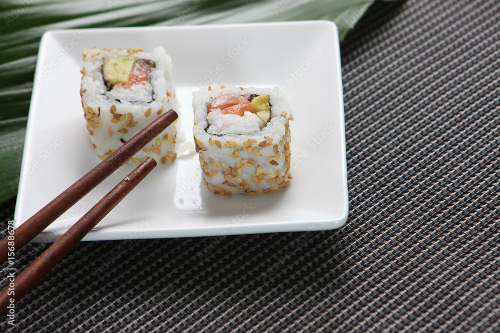 Sushis dans une petite assiette avec baguettes asiatiques Sushis dans une petite assiette avec baguettes asiatiques