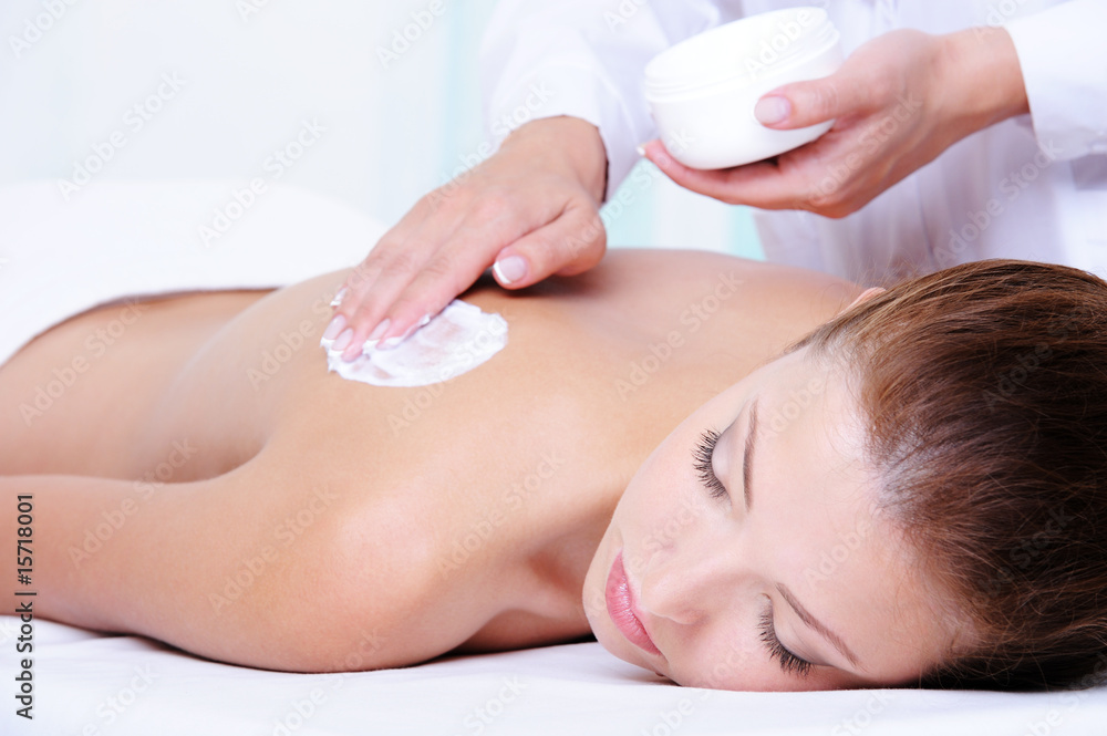 Naklejka premium Applying moisturizing cream on the female back