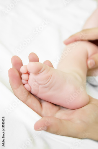 Woman hand holds baby leg