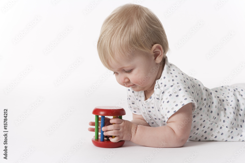 Baby girl lying on her belly looking at a toy