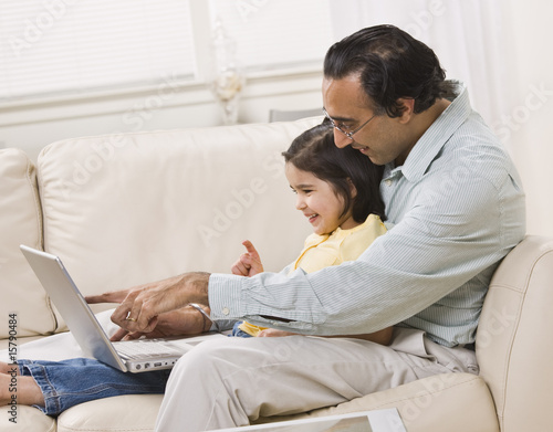 Indian Father and Daughter Look at Laptop Together