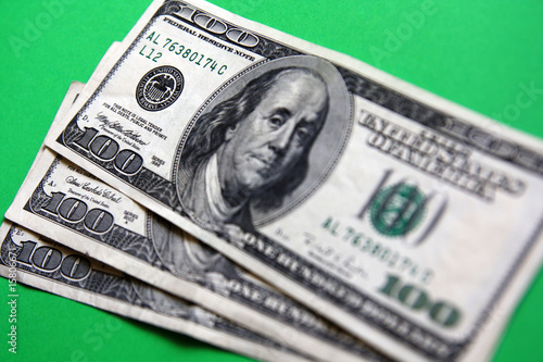 three 100 dollars banknote on the green background