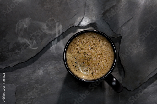 steamed spresso coffee in black cup on black stone background photo