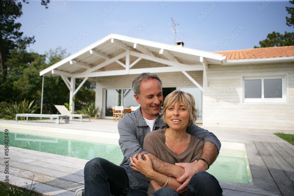 Couple souriant devant une maison
