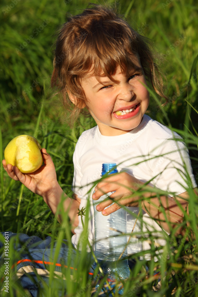 girl with plastic bottle eats green apple in grass girl with plastic bottle eats green apple in grass