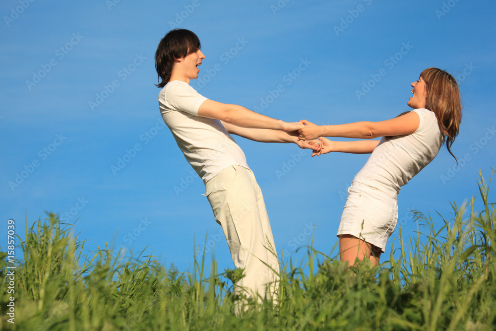 girl and  guy stand on grass having joined hands