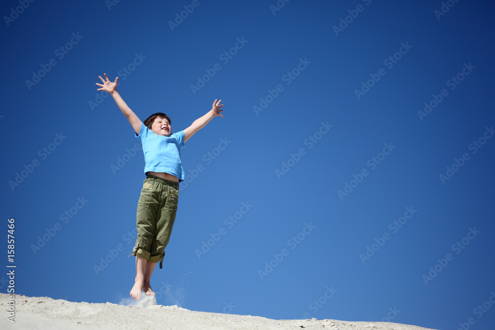 boy jumps on sand with lifted hands boy jumps on sand with lifted hands