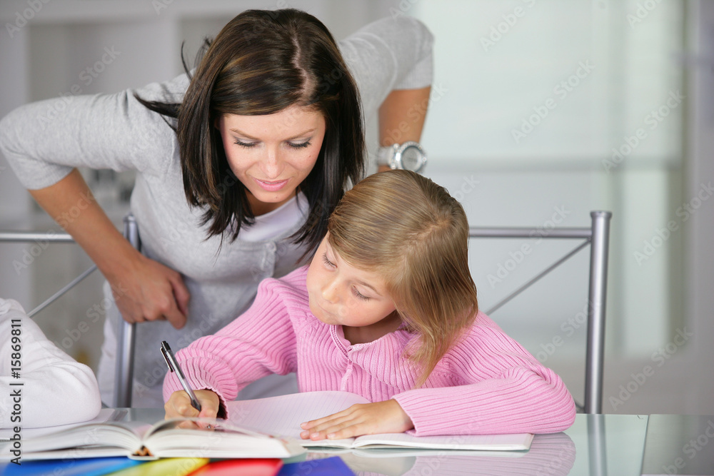 Portrait d'une femme aidant une petite fille à faire ses devoirs Portrait d'une femme aidant une petite fille à faire ses devoirs