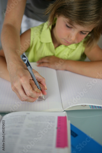 Femme aidant une petite fille à écrire sur un cahier d'écriture