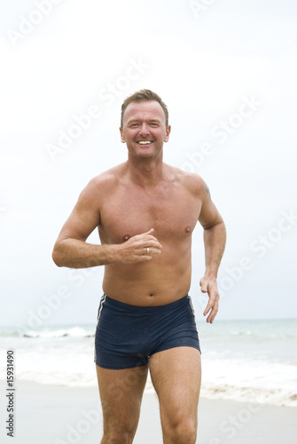 happy forties man jogging on beach.