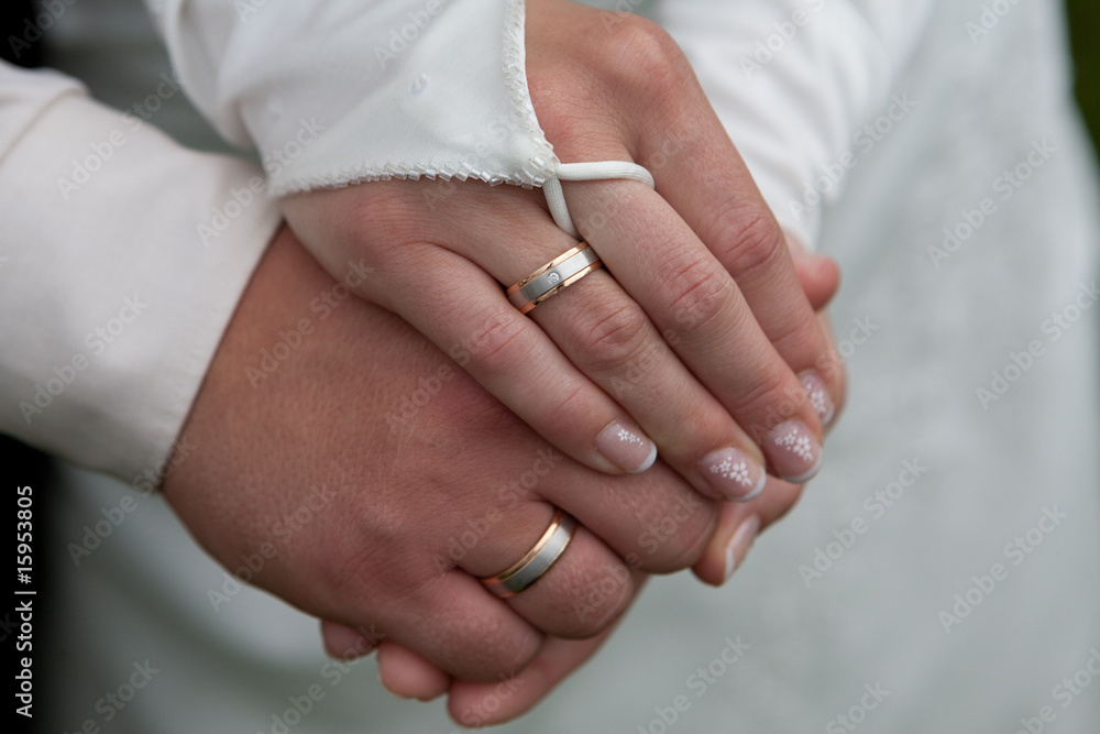 Hände von einem Hochzeitspaar mit Ring und Kleid
