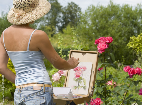 Photo Young woman painting roses in the garden