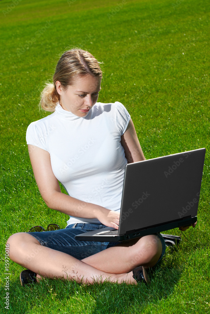 The girl with laptop on a green lawn The girl with laptop on a green lawn