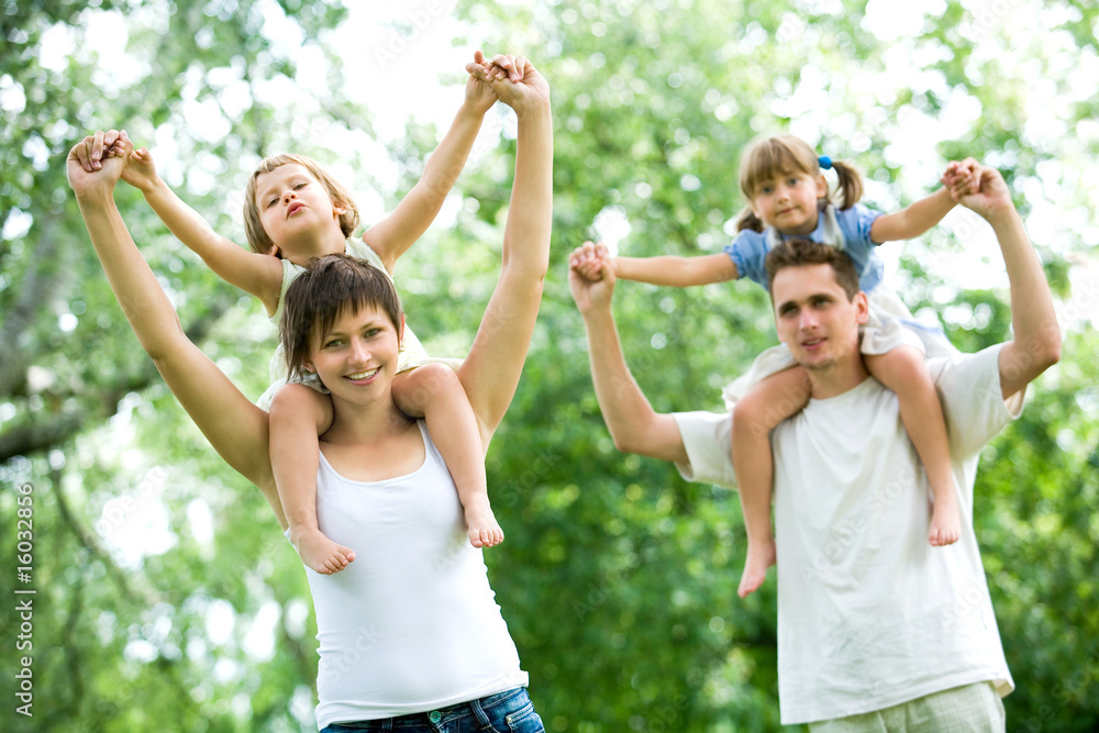 Couple giving children piggyback rides Couple giving children piggyback rides