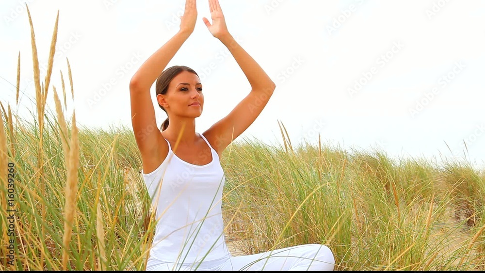 Femme faisant du yoga dans des herbes hautes