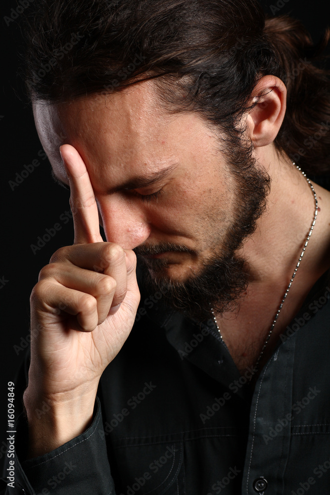 Portrait of young man touching his forehead with index finger Portrait of young man touching his forehead with index finger
