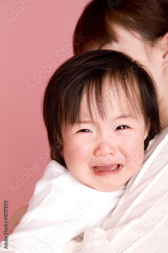 母親に抱っこされて泣いている赤ちゃん