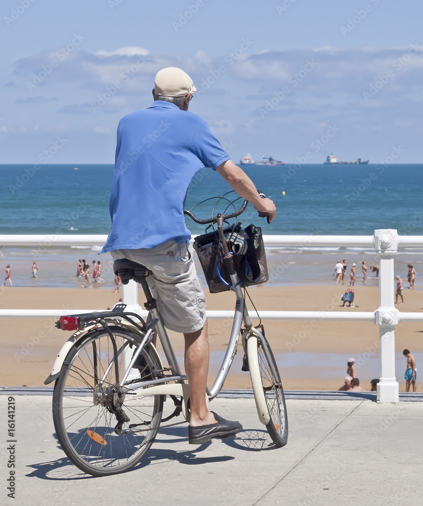 Anciano en bicicleta frente a la playa