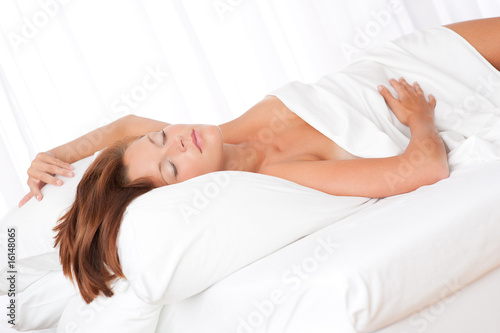 Brown hair woman sleeping on white bed